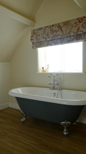 a large bath tub in a bathroom with a window at The Colesbourne Inn in Colesbourne