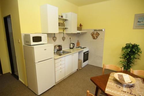 a kitchen with white cabinets and a microwave and a table at Chata Javorina in Javorník