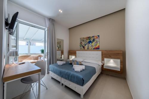 a bedroom with a bed and a desk and a window at Artemide Hotel in San Vito lo Capo