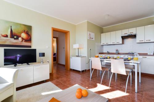 a kitchen with white cabinets and a table with chairs at Cecilia Apartments in Lun