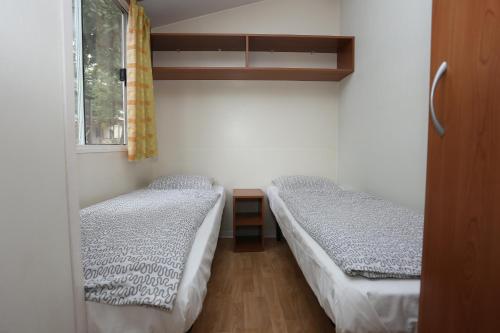 Cette petite chambre comprend 2 lits et une fenêtre. dans l'établissement Mobile Homes Comfort CAPRI Bijela Uvala, à Poreč