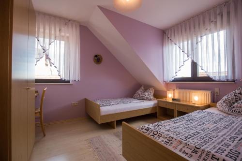 BurkardrothにあるFerienwohnung Arnoldの紫の壁と窓が特徴の客室で、ベッド2台が備わります。