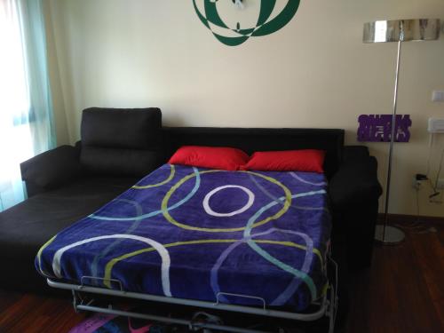 a bed with a purple comforter and a black couch at Apartamento La Gloria in Gibaja