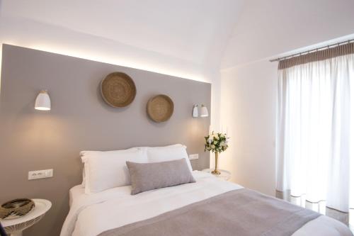 a white bedroom with a bed and a window at Louis Studios Santorini in Kamari