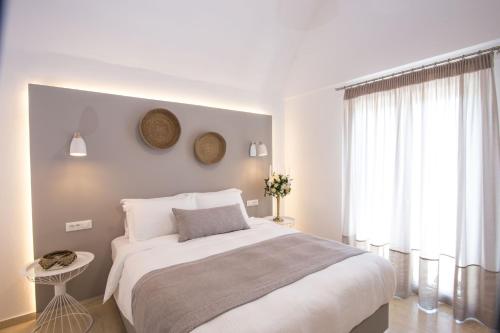 a white bedroom with a large bed and a window at Louis Studios Santorini in Kamari