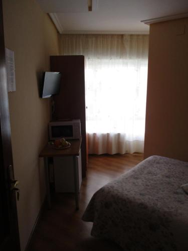 a bedroom with a bed and a table with a window at Hostal Becares in Palencia