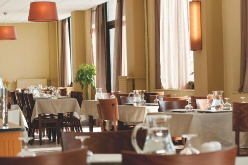 une salle à manger avec tables, chaises et fenêtres dans l'établissement VTF Le Grand Hotel, à Montgenèvre