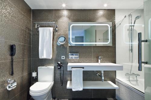 a bathroom with a sink and a toilet and a mirror at Vincci Gala in Barcelona