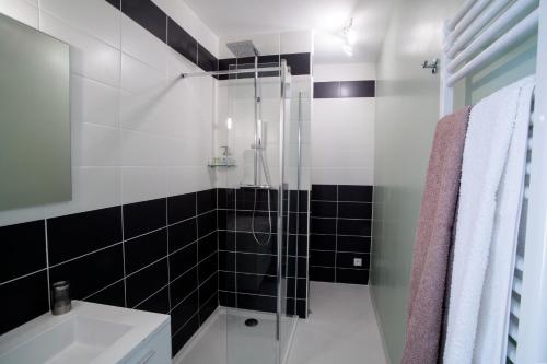 シャナにあるAu Clos Beausejourの黒と白のタイル張りの壁のバスルーム(シャワー付)
