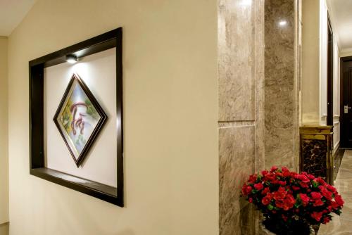 a mirror hanging on a wall with a vase of flowers at Binh Anh Hotel in Hanoi