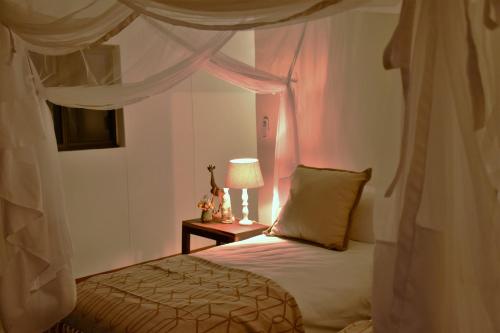 a bedroom with a bed and a table with a lamp at Cheetah View Lodge in Otjiwarongo