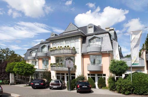 un grand bâtiment avec des voitures garées devant lui dans l'établissement Hotel Tandreas, à Giessen