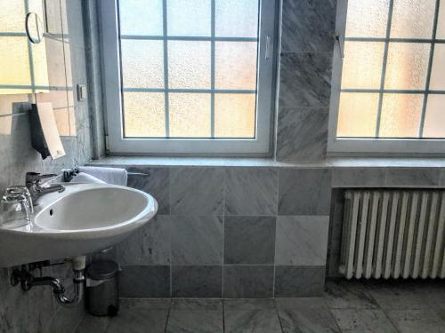 a bathroom with a sink and two windows at Hotel Kölner Hof in Dormagen