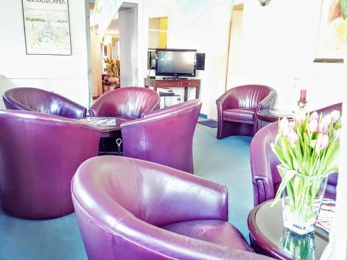 a waiting room with purple chairs and a table with flowers at Hotel Kölner Hof in Dormagen