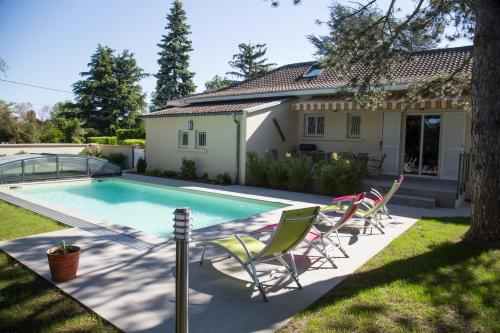 een zwembad met stoelen en een huis bij Au Clos Beausejour in Chanas