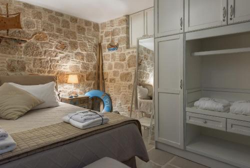 a bedroom with a bed and a stone wall at Admiral's House in Halki