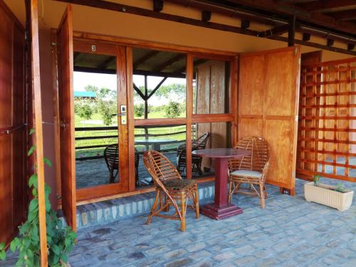 a patio with chairs and a table and windows at Salaš Farma 47-Miris Dunja in Čenej