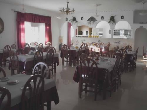 a dining room with tables and chairs and a room with a chandelier at Nikos Hotel in Karterados
