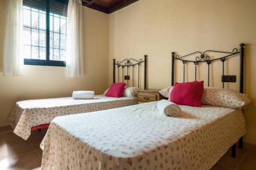 アンテケラにあるCasa Rural EL CANAL CDのピンクの枕が付いたベッドルームのベッド2台