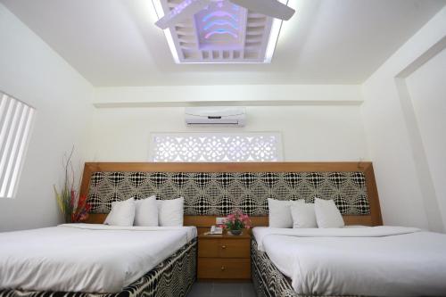 two beds in a room with white walls and a skylight at Nagar Valley Hotel Ltd. in Dhaka