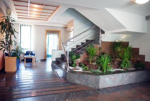 a lobby with a staircase with plants at Hotel Cubic in Laktaši