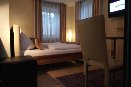 een slaapkamer met een bed, een stoel en een televisie bij Pension Leichtfried in Amstetten