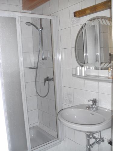a white bathroom with a shower and a sink at Pension Waldhof in Koppl