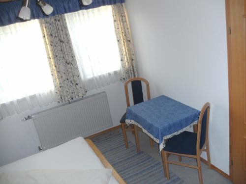 a room with a table and a chair and a bed at Pension Waldhof in Koppl