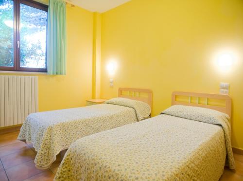 アッシジにあるOstello Fontemaggioの黄色い壁の客室内のベッド2台