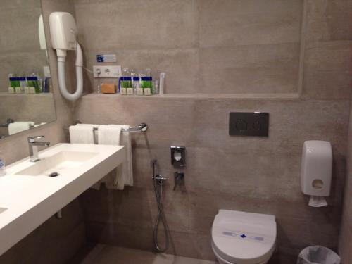 a bathroom with a sink and a toilet and a mirror at Las Rocas Playa Hotel in Castro-Urdiales