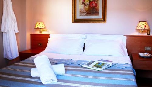 a hotel room with a bed with a book on it at Hotel Tirreno in Castiglione della Pescaia