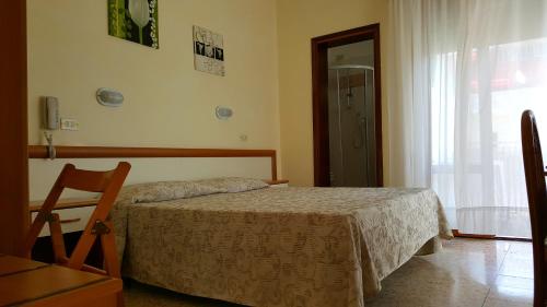 a bedroom with a bed and a chair and a window at Hotel Marietta in Caorle