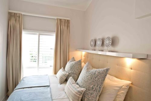 a bedroom with a bed with pillows and a window at D3 Sea Lodge - by Stay in Umhlanga in Durban