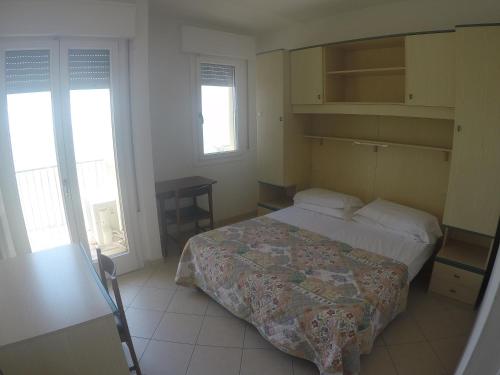 カオルレにあるPresident Frontemare - Agenzia Cocalのベッドルーム1室(ベッド1台、テーブル、窓2つ付)