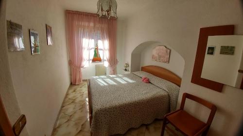 una camera con letto, finestra e sedia di Villa La Favola a Ischia