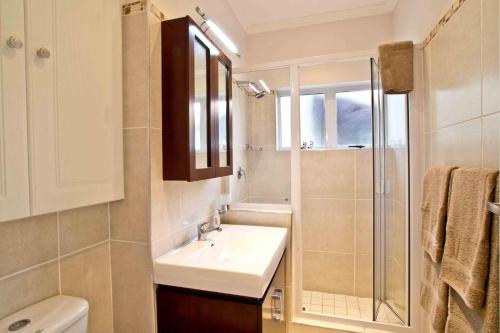 a white bathroom with a sink and a shower at D3 Sea Lodge - by Stay in Umhlanga in Durban