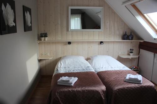 a small bedroom with two beds and a mirror at Hof van Lutten in Lutten