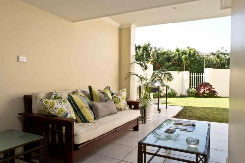 D3 Sea Lodge - by Stay in Umhlanga في ديربان: غرفة معيشة مع أريكة وطاولة زجاجية