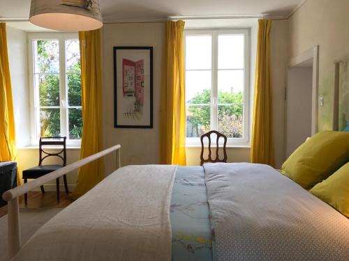 a bedroom with a large bed and two windows at L'Ermitage in Saint-Vaast-la-Hougue