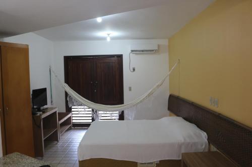 a bedroom with a bed and a tv in it at Marambaia Apart Hotel in Natal