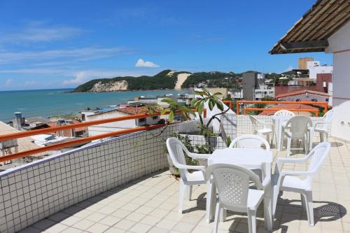 a patio with white tables and chairs and the ocean at Marambaia Apart Hotel in Natal