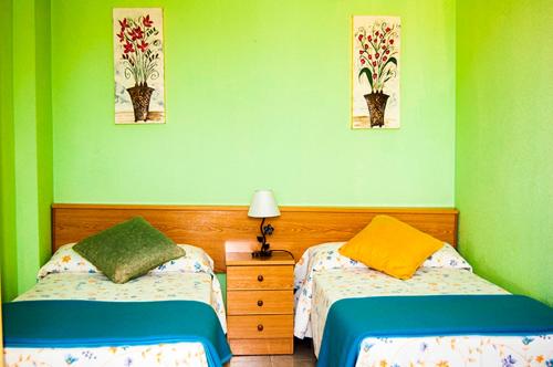 two beds in a room with green walls at El Encinar de playa de la arena in Isla