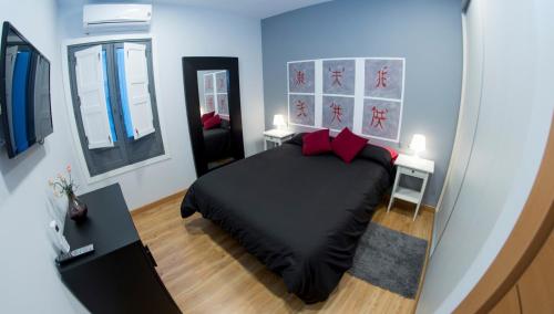 a bedroom with a black bed with red pillows at Ocho Home Apartamentos in Zamora