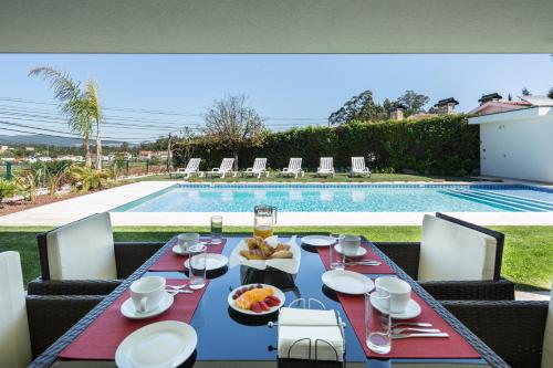 a dining table with food on it next to a pool at Gallo`s House in Barcelos