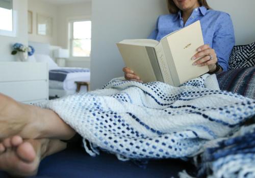a woman laying on a bed reading a book at The Sea Breeze Inn in Middletown