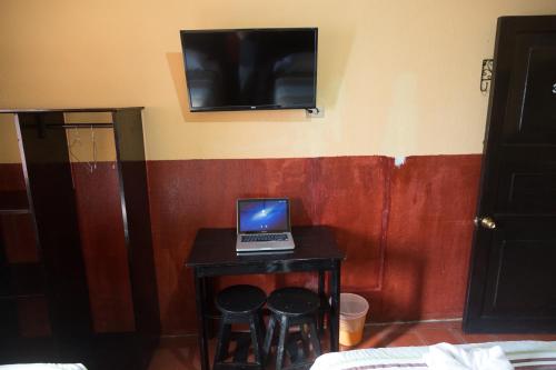 un ordenador portátil sentado en una mesa pequeña con dos taburetes en Hotel Ajau en Guatemala