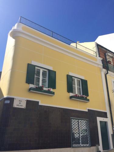 a yellow building with two windows and green shutters at Madragoa - PLUS in Lisbon