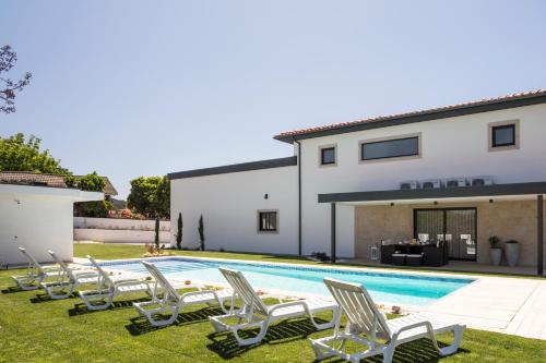 a pool with lawn chairs and a house at Gallo`s House in Barcelos