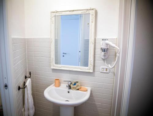 a white bathroom with a sink and a mirror at La Via Del Mare in Palinuro