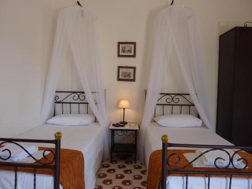 una camera con due letti e un tavolo con una lampada di Villa Niki a Serifos Chora